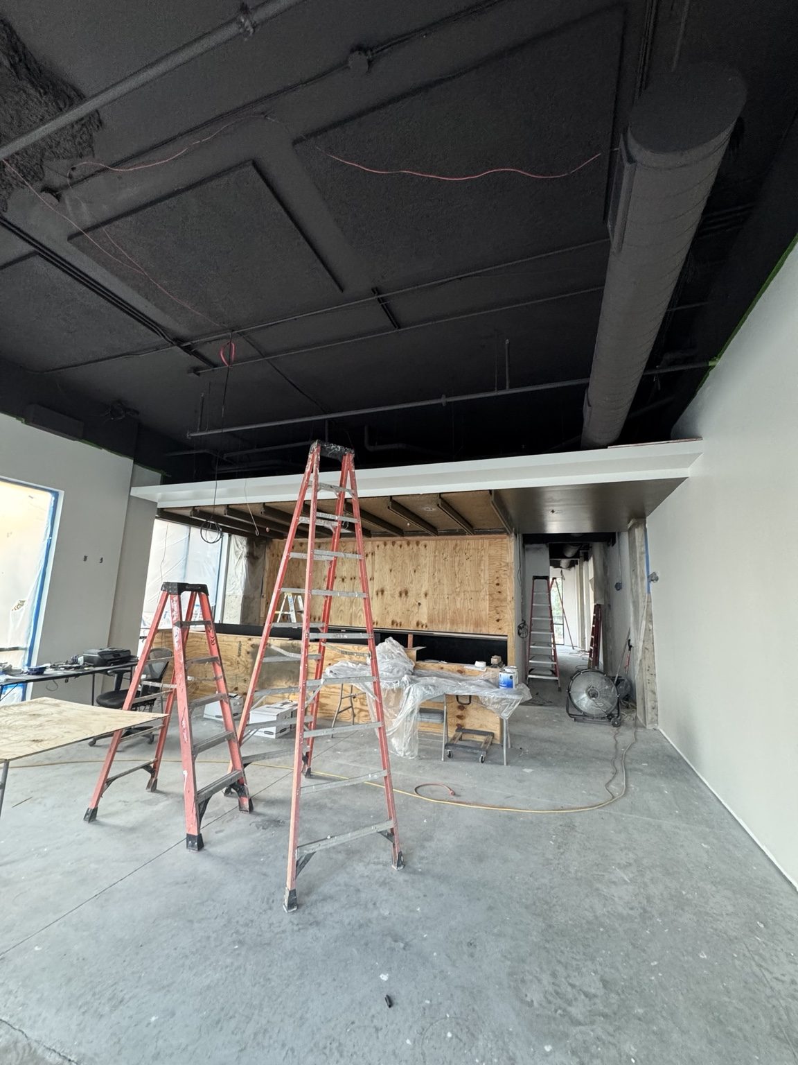 Bar painting and cleanup progress at Libations with ladders in the space