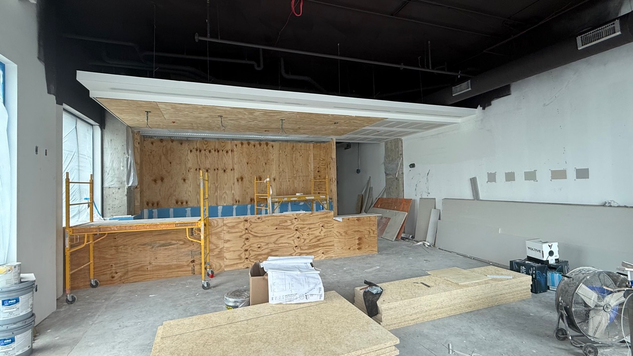 Updated construction photo showing counter rough-in work and plywood framing