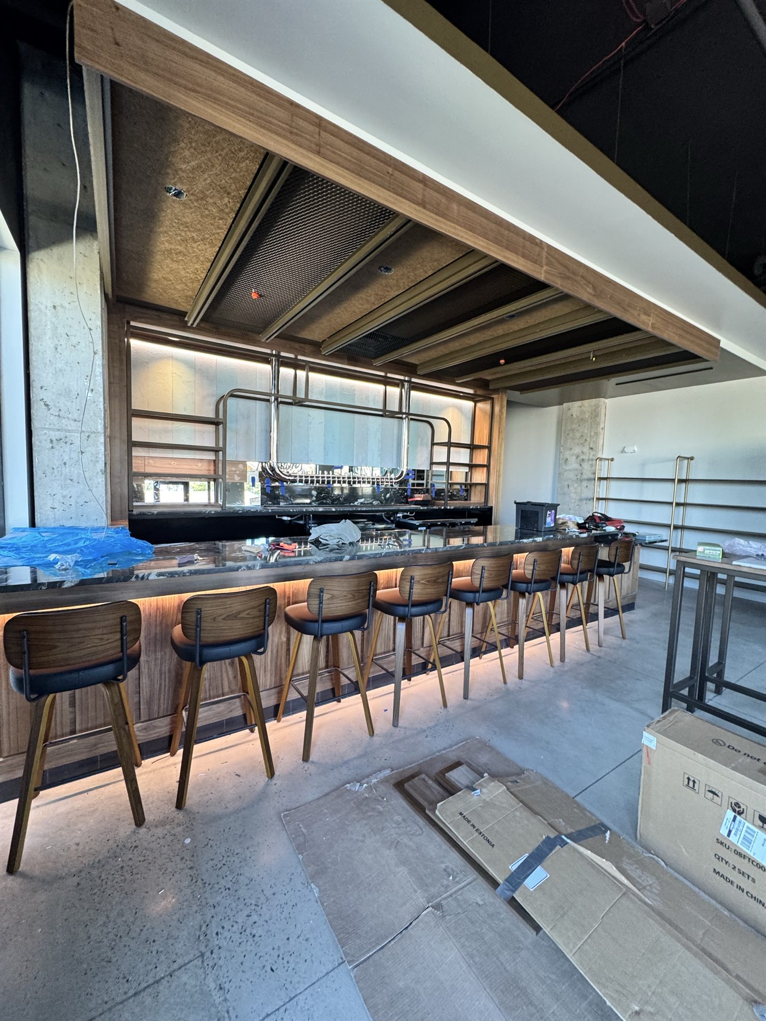 Assembled wood and black bar chairs lined up at the finished Libations bar