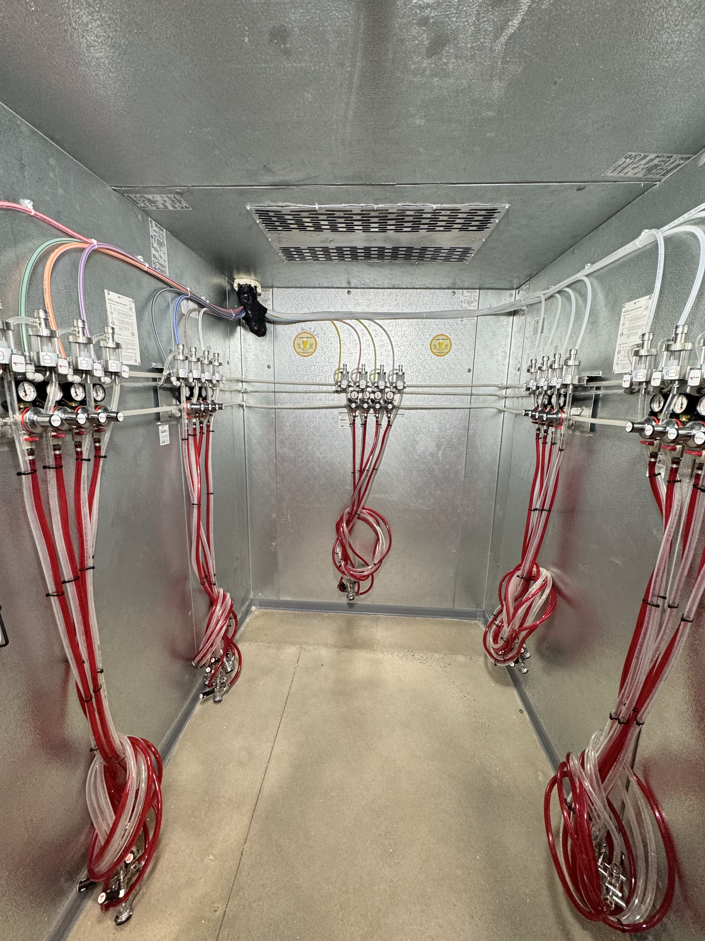 Beverage tap lines and regulators installed inside the walk-in cooler at Libations