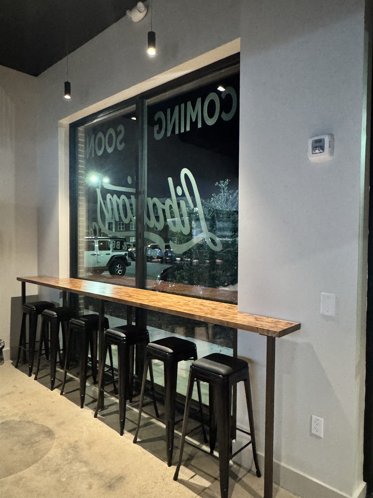 Window bar with stools overlooking the front windows at Libations